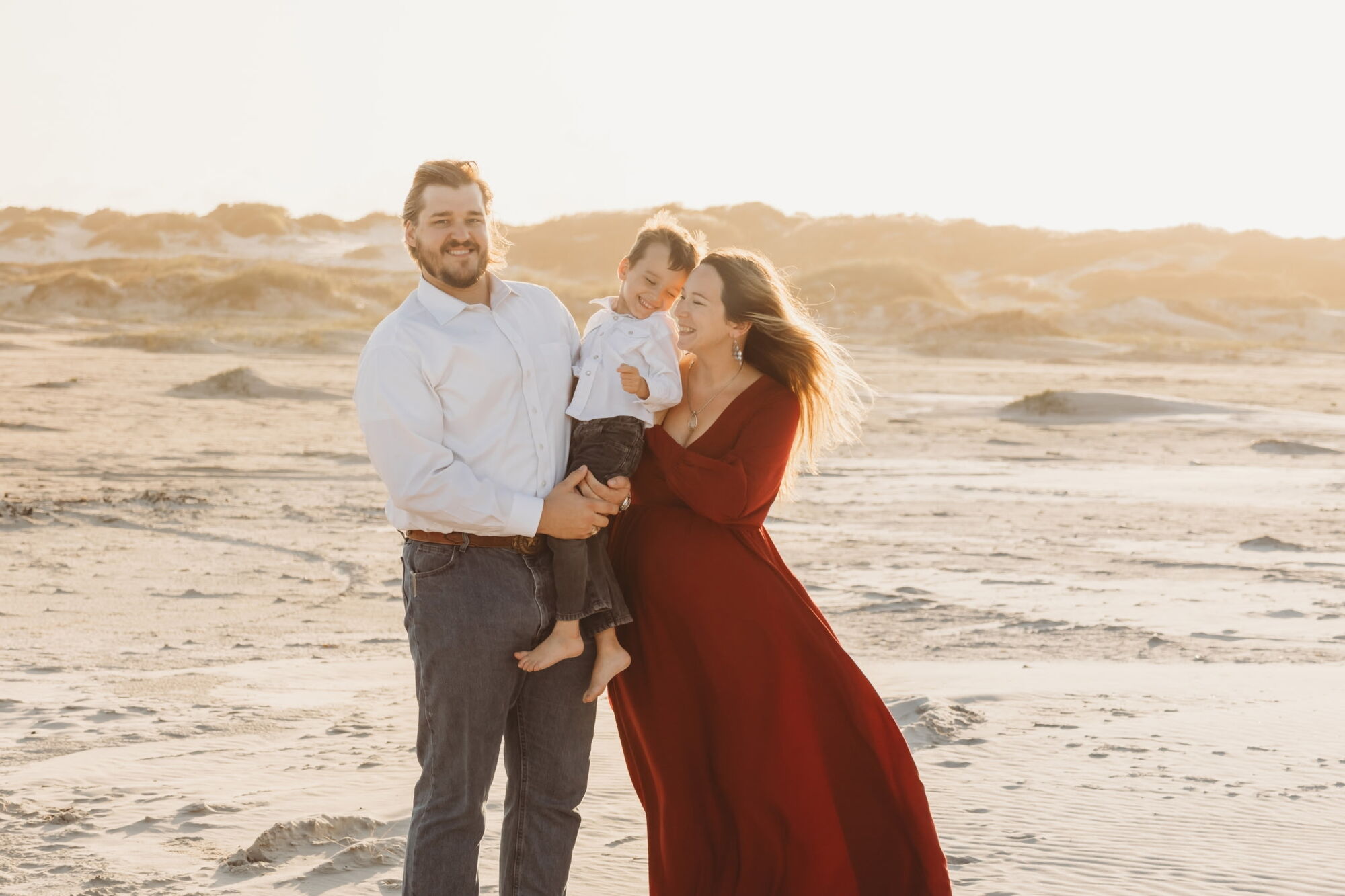 Samuel, wife, and son standing on the beach posing for photo
