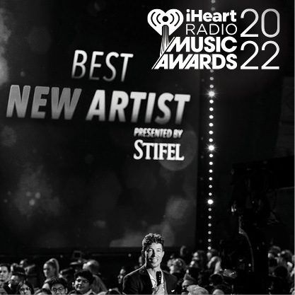 Black and white image of Sean White announcing to an audience at the IHeart Radio Awards presented by Stifel