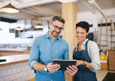 Business owner looking over data on ipad with employee