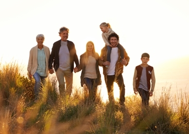 Multi-generation family walking in field and holding hands